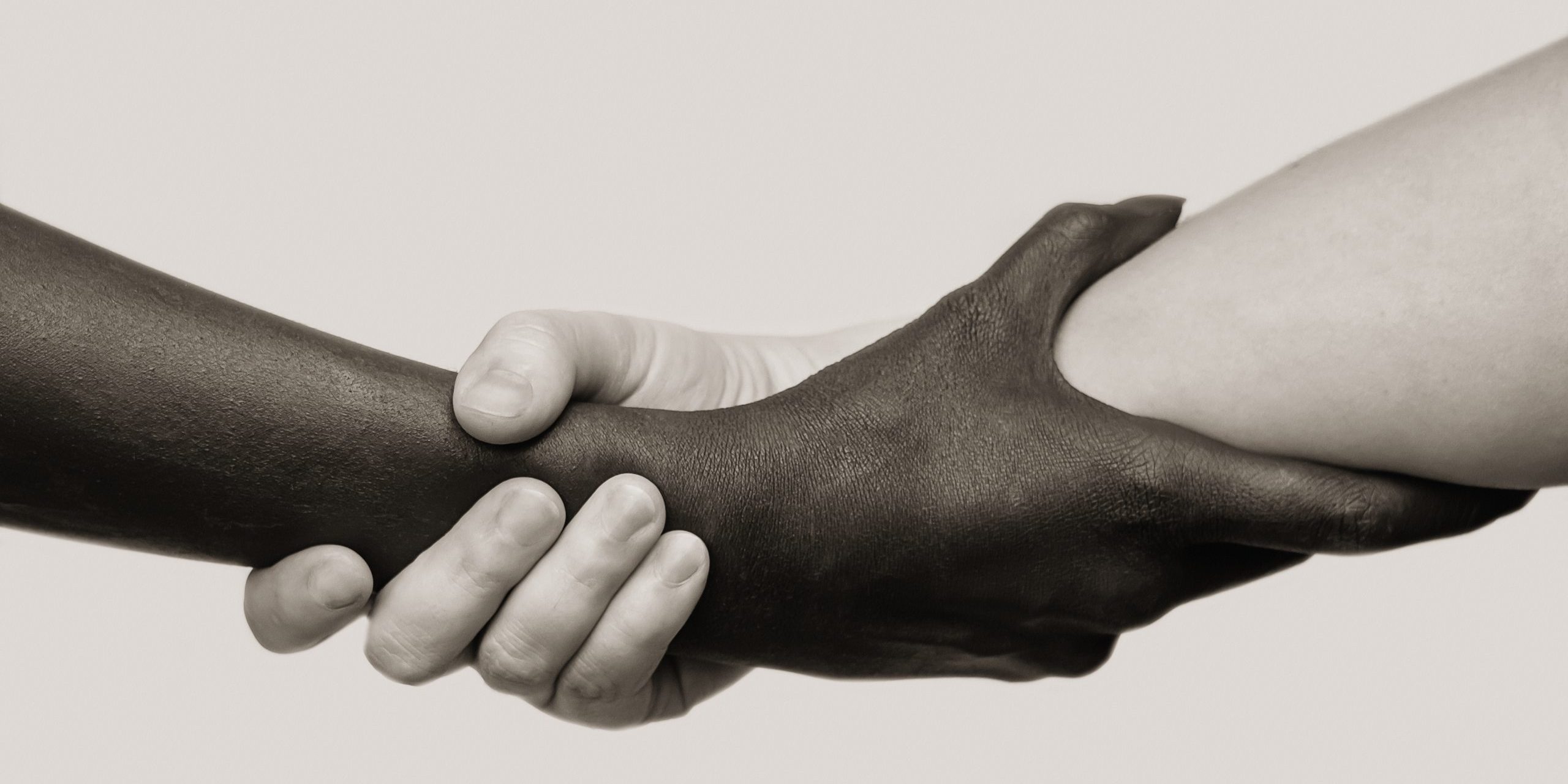 Black-and-white human arms wrapped tightly around each other . The concept of combating racism, friendship and respect .Selective focus, close-up, black and white photography, isolated background